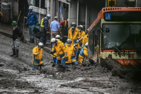 Charly Triballeau / AFP Police search for missing people at the scene of a deadly landslide, in Atami, Japan, on 4 July 2021