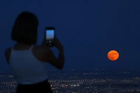 Jose Luis Gonzalez/Reuters A woman takes a picture of the moon