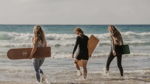 Evie Johnstone Bodyboarders going into the sea