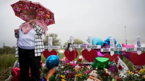 The Washington Post via Getty Images Katy Novak helps to lead dozens of people standing in the rain in prayer and song at the memorial crosses near the Sutherland Springs First Baptist Church one week after 26 people were killed inside in Sutherland Springs, Texas on November 12, 2017