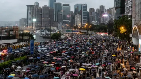 Getty Images Over a million protesters, carrying umbrellas, march through the streets of Hong Kong with the city's skyscrapers in the background