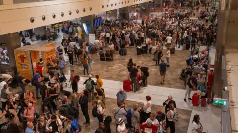 Getty Images Passengers wait at Tenerife South Reina Sofia Airport after flights were cancelled due to a sandstorm