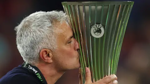Roma boss Jose Mourinho kisses the Europa Conference League trophy