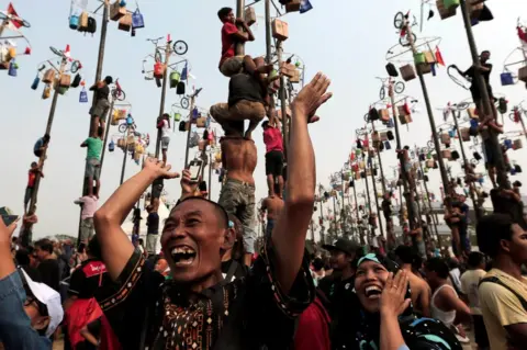 Beawiharta/ Reuters A couple reacts as their colleague wins a bicycle during greased pole competition during the celebration of Independence Day at Ancol Dreamland Park in Jakarta, Indonesia