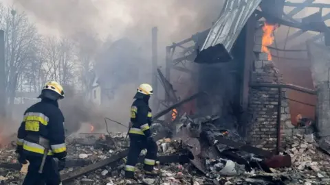 Getty Images Firefighters are seen at the site after air strikes hit civil settlements in Dnipro, 11 March 2022.