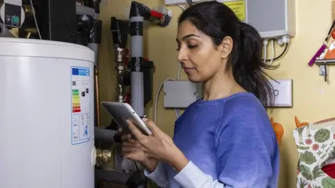 Getty Images Woman changing thermostat on boiler