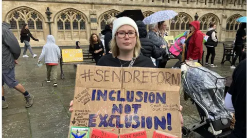 BBC A protester holds up a placard saying "Inclusion not exclusion!" at the protest