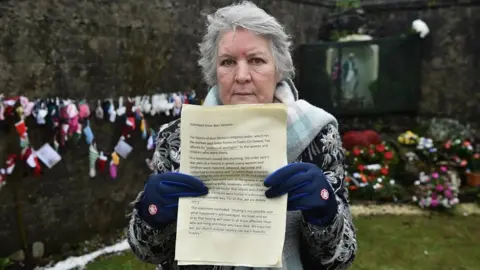 Charles McQuillan Carmel Larkin holding apology at Tuam site