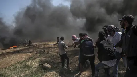 EPA Palestinians protesters pulling barbed wire fence installed by Israeli army along the border during clashes after protests near the border with Israel in the east of Gaza Strip