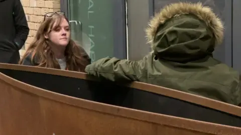 Ella speaking to an anonymous man who has been sleeping on a bench