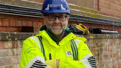 BBC John Rowlands in his Environment Agency high vis jacket and safety helmet