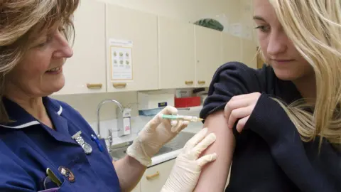 DR P. MARAZZI/SCIENCE PHOTO LIBRARY Nurse gives HPV vaccination to school girl