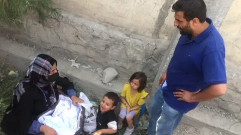 Khalid, a former interpreter for the British army, waits outside with his family