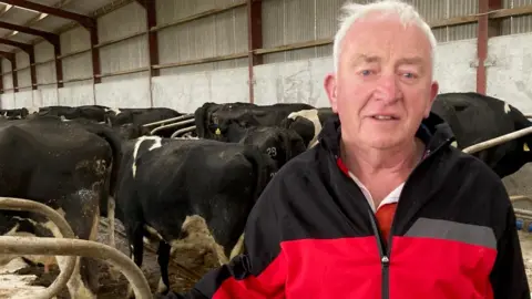 BBC John Carson stood with cows