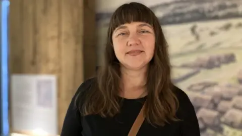 Natalia Kostina wears a black top and looks into the camera