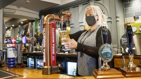 PA Media Melanie Scott pulls a pint at the Black Bull pub in Haworth, West Yorkshire