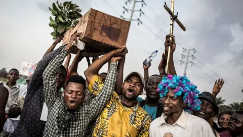 AFP Supporters of Martin Fayulu, the runner-up in Congolese elections, hold up a coffin with "Good Bye Felix" as they protest in the street on 21 January 2019 in Kinshasa, DR Congo