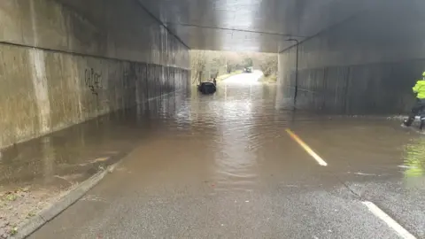 South Wales Police A car stuck in flood water under a bridge in Swansea