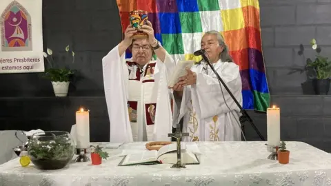 Olga Lucía Álvarez at the altar holding a chalice in her hands