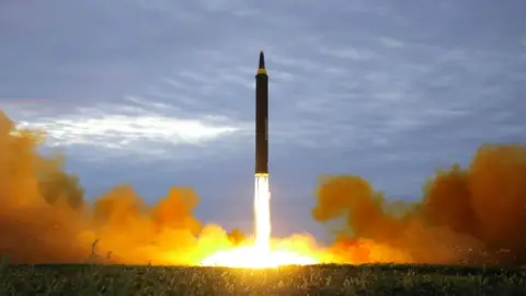 KCNA A missile is seen taking off from a grassy field in a burst of burning fuel and smoke