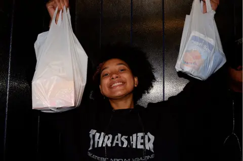 Rachael Simoes  A girl holds up bags of takeaways