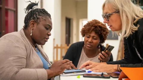 Kate Stanworth Osas Egbon (L) and other volunteers doing admin at the food bank in Palermo, Sicily in Italy