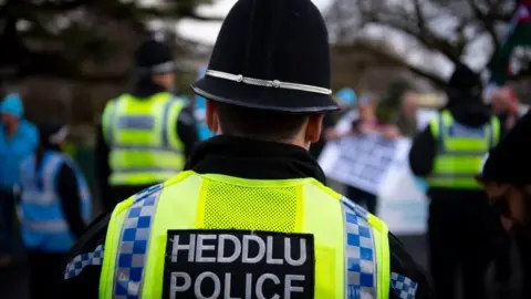 Getty Images Welsh police officer in helmet and high-vis vest with words Heddlu Police on back at an event