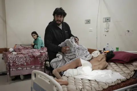 Mohammed Shahin/BBC Rafeeq Dughmoush is assisted by his uncle Mahmoud. He lost one leg below the knee in a strike on his family home. (Mohammed Shahin/BBC)