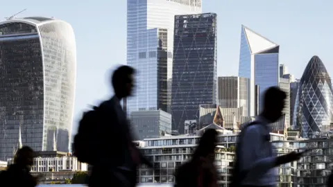 Getty Images Business people walking to work with view of the financial district behind in London, England