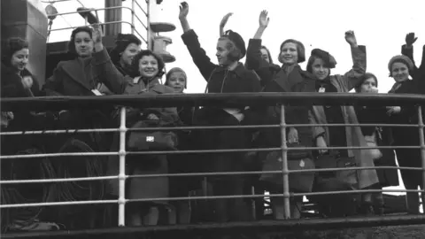 Fred Morley/Fox Photos/Getty Images Children wave from the deck of a boat