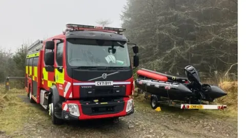 BBC A fire engine next to a rescue boat