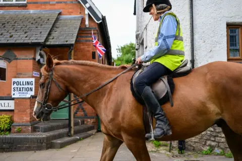 Getty Images Woman passes polling station on horseback in Uffculme, Devon