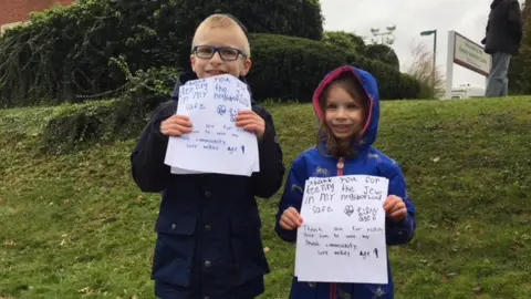 Mikey and Lily hold signs thanking the police after Pittsburgh shooting