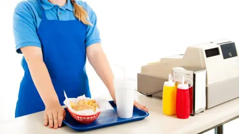 Getty Images Teenage cashier serving fast food in a restaurant (posed image)