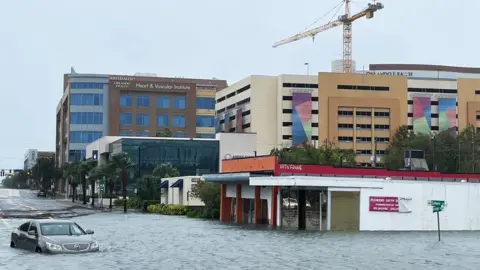 EPA A vehicle sits partially submerged in a flooded downtown following Hurricane Ian, in Orlando