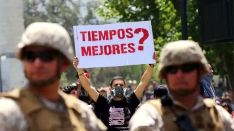 AFP Un manifestante sostiene un cartel que dice "¿Mejores tiempos?" Mientras los soldados hacen guardia en la Plaza Italia en Santiago, Chile, el 21 de octubre de 2019.