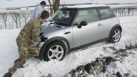 Crown Copyright Man pushes car out of snow