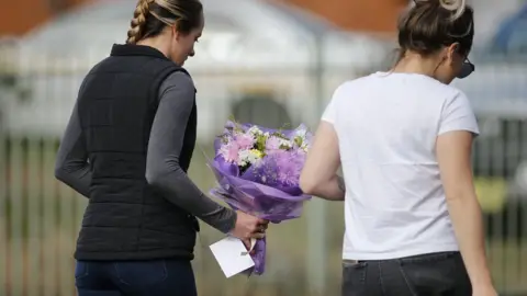 EPA Two women bring flowers and a card to the scene of the fire