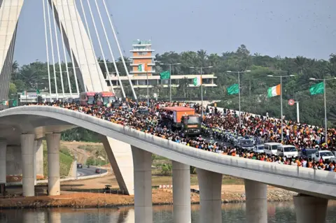 SIA KAMBOU/AFP Ivory Coast players, winners of the 2024 African Cup of Nations, parade in a vechile on the Alassane Ouattara bridge in Abidjan.