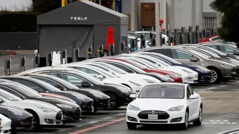 Reuters A Tesla Model S electric vehicle drives along a row of occupied superchargers at Tesla"s primary vehicle factory after CEO Elon Musk announced he was defying local officials" restrictions against the coronavirus disease (COVID-19) by reopening the plant in Fremont, California, U.S. May 12, 2020.
