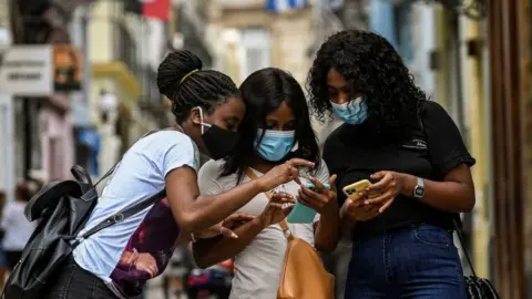 Getty Images Cubans check their phones after authorities restored internet access, 14 July 2021