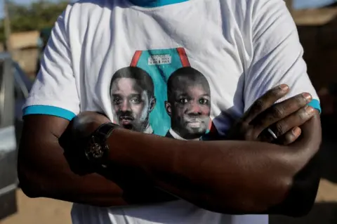 ZOHRA BENSEMRA/REUTERS An opposition supporter wears a T-shirt showing political figures on 12 March.