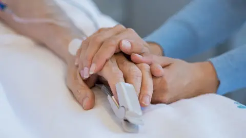 Getty Images Patient's hand being held by woman