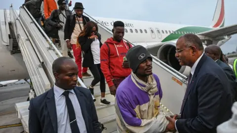 Getty Images Ivorian Prime Minister Patrick Achi welcoming migrants repatriated from Tunisia