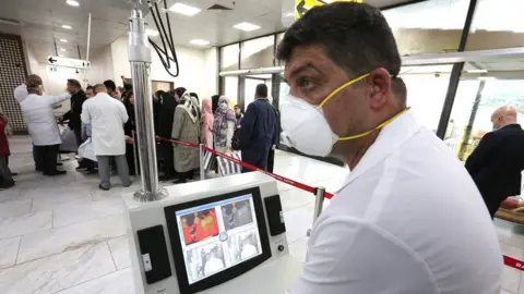 EPA Members of Iraqi medical team check passengers upon arrival from Iran at Baghdad international airport