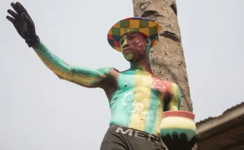 AFP A Togolese man with body paint in the colours of the national flag and the letter C92 referring to the return to the 1992 Constitution in Togo and for the departure of the current president, watch a protest rally by women marching against Togo"s president in the capital Lome on January 20, 2018.