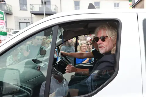 PA Media Bob Geldof rides in a taxi as part of the funeral cortege for Sinead O'Connor as the procession passes through her former hometown of Bray, Co Wicklow on 8 August 2023