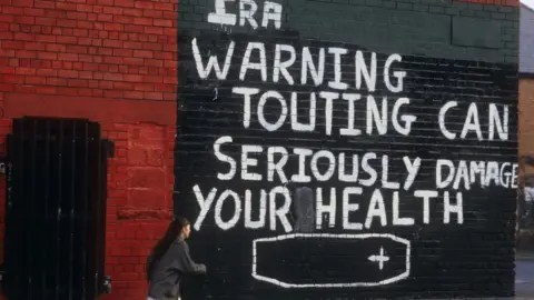 Getty Images Grafitti in Belfast reads: IRA warning - touting can seriously damage your health