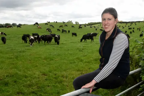 David Bagnall / Alamy Stock Photo Liz Haines sits on a fence in front of a field