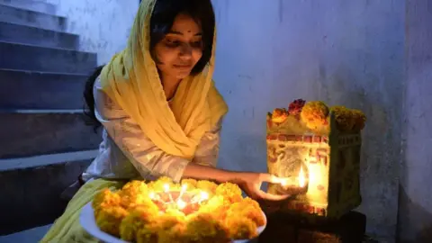 Getty Images An Indian woman Rishitha places earthen lamps or 'diyas' at her home on the eve of Diwali Festival in Hyderabad on October 18, 2017.